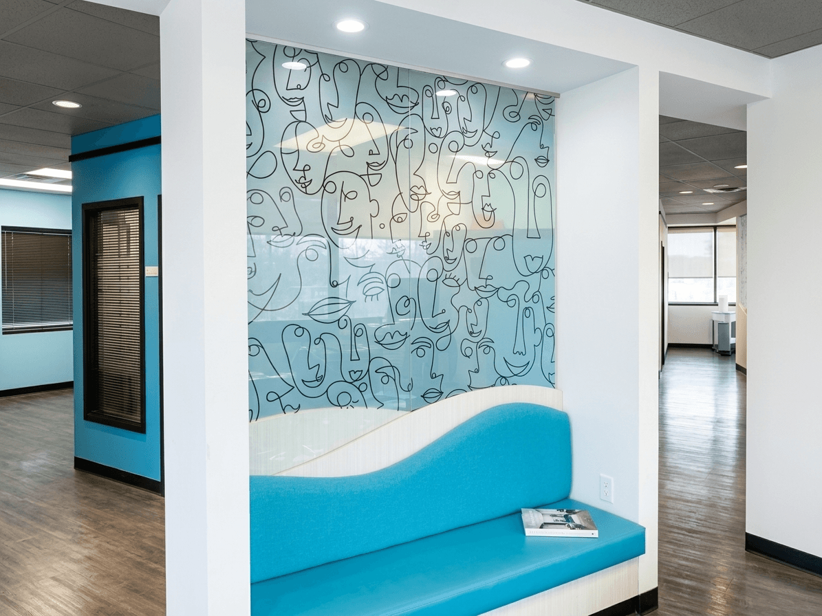 The waiting nook, with a curved blue bench beneath an illustrated glass panel